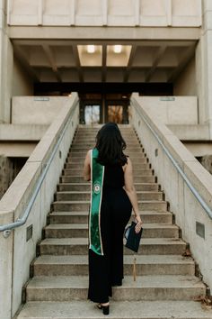 a woman walking up some stairs with a green sash around her neck and handbag