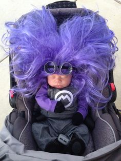 a doll with purple hair and glasses in a stroller bag, wearing sunglasses on top of it's head