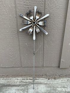 a clock made out of forks and spoons on the side of a building