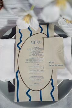 a plate with a menu on it and napkins next to flowers in the background