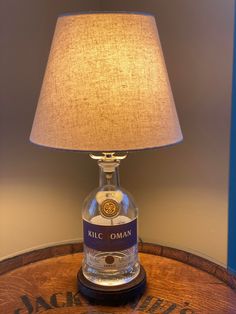 a lamp that is sitting on top of a table next to a glass bottle with a label on it