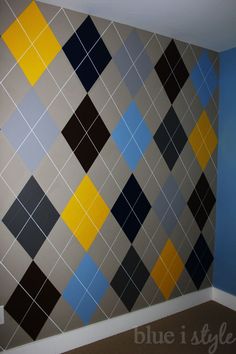 an empty room with blue walls and yellow and black squares painted on the wall behind it