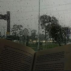 an open book sitting on top of a window next to a rain covered street sign