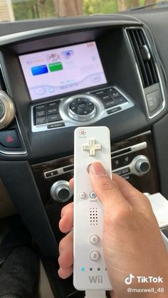 a person holding a remote control in their hand while sitting in a car with the steering wheel down