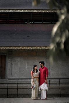 two people standing next to each other near a building