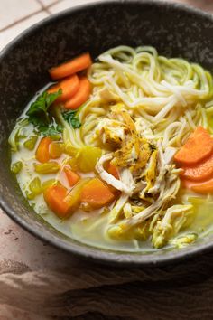 a bowl filled with noodles and carrots on top of a table