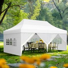 a white tent set up in the grass with tables and chairs under it, surrounded by yellow flowers