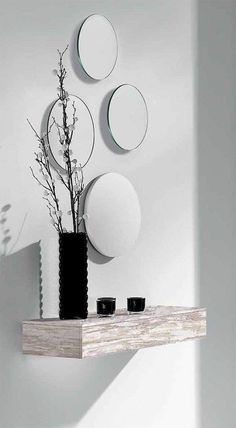 three circular mirrors on the wall above a shelf with two cups and a plant in it