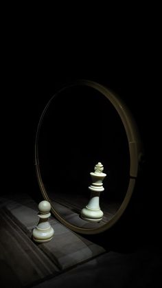 a mirror that has some white chess pieces in front of it and a black background