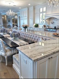 a large kitchen with marble counter tops and white cabinets