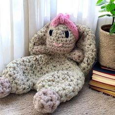 a crocheted elephant laying on top of a rug next to a potted plant