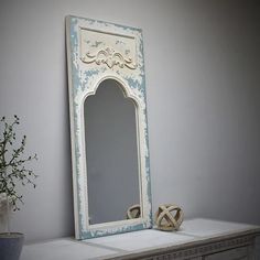 a mirror sitting on top of a dresser next to a potted plant