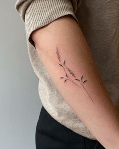 a woman's arm with a small flower tattoo on the left side of her arm