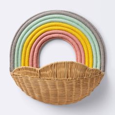 a wicker basket with multicolored rings hanging from it's side on a white wall