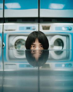 a woman's face is reflected in the reflection of a washing machine