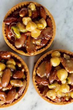 three pies filled with nuts sitting on top of a marble countertop next to each other