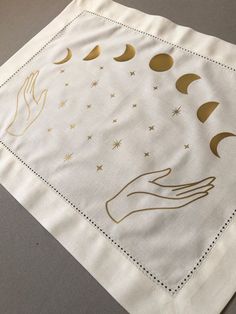 a white napkin with gold hand and moon designs on it, sitting on top of a table