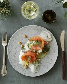 a white plate topped with food next to silverware and wine glasses on top of a table