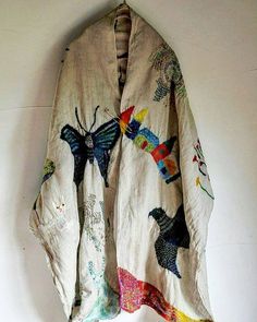 an old jacket hanging on the wall with colorful butterflies and moths all over it's fabric