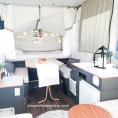 the inside of a camper with a kitchen and dining table in it, next to a stove top oven