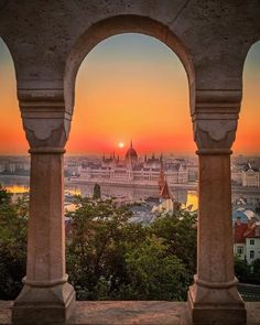 the sun is setting over a city from an arch in a building with arches on it