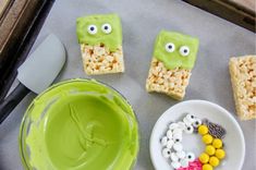 rice krispy treats with eyes and googly eyes are on a tray next to a bowl of candy