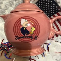 a pink teapot with an image of a cartoon character on it and streamers