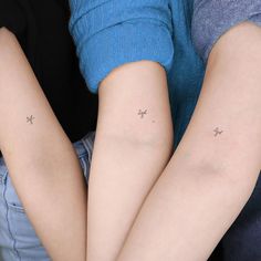 two people with small tattoos on their arms, one is holding the other's arm