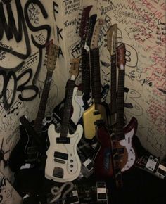 a bunch of guitars sitting on top of each other in front of graffiti covered walls