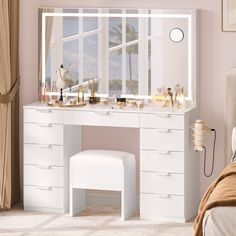 a bedroom with a white vanity table and stool in front of a large window overlooking the ocean