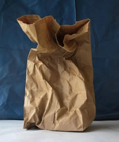 a brown paper bag sitting on top of a white table next to a blue wall