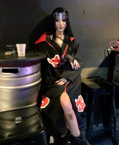 a woman sitting on top of a stool next to a metal barrel filled with liquid