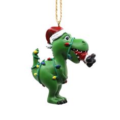 a green christmas ornament with a dinosaur wearing a santa hat and holding a candy cane