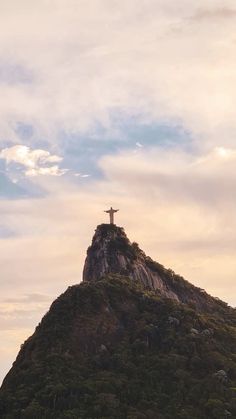 a person standing on top of a mountain with a cross in the middle of it