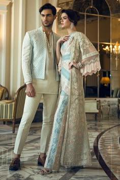 a man and woman standing next to each other in front of a large room with chandeliers