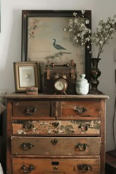 an old dresser with flowers and pictures on it