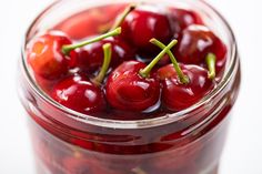 a glass jar filled with cherries on top of a table