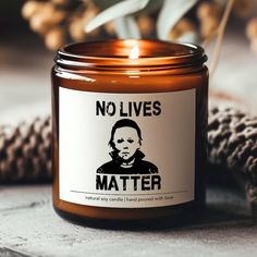 a candle with a sticker on it that says no lives matter, next to pine cones