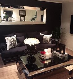 a living room with black couches and white flowers on the coffee table in front of it