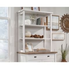 a white bookcase with drawers and pictures on the wall