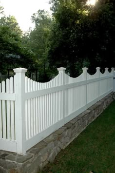 a white picket fence in front of a stone wall