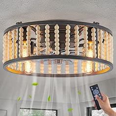 a person holding a remote control in front of a chandelier with beads hanging from it