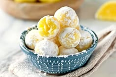 a blue bowl filled with powdered sugar covered donuts