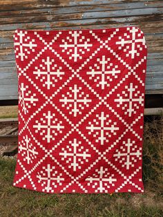 a red and white quilt sitting on top of a wooden bench