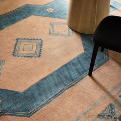 a chair sitting on top of a rug next to a wooden table with a vase