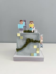 a cake made to look like people on top of a mountain with moss growing out of it