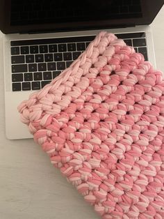 an open laptop computer sitting on top of a white table next to a pink blanket