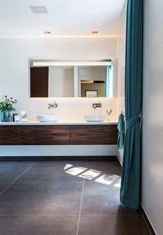 a bathroom with two sinks and a large mirror in it's center, next to a curtained window