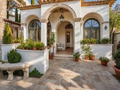 a white house with lots of potted plants on the front porch and entryway