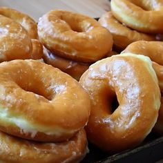 several glazed donuts stacked on top of each other in a black box with white icing